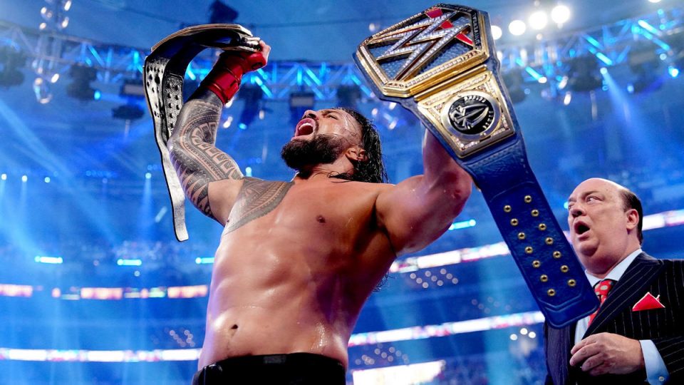 Roman Reigns holding up both world titles after beating Brock Lesnar at WrestleMania