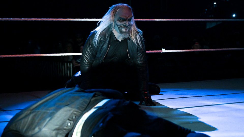 Uncle Howdy crawling in the ring in front of Bray Wyatt