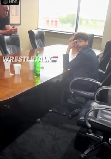 Shane McMahon and Tony Khan meeting at a wooden table